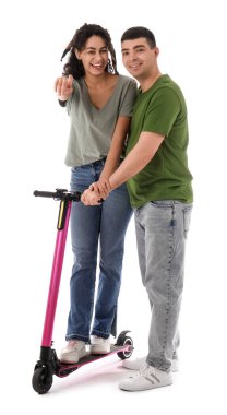 Modern elektrikli scooter 'ı olan güzel genç çift beyaz arka plandaki bir şeyi işaret ediyor.