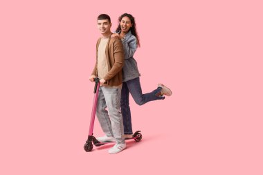Pembe arka planda modern elektrikli scooter kullanan güzel bir çift.