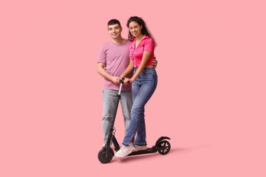 Pembe arka planda modern elektrikli scooter kullanan mutlu genç bir çift.