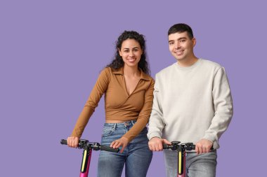 Mor arka planda modern elektrikli scooterları olan güzel genç bir çift.