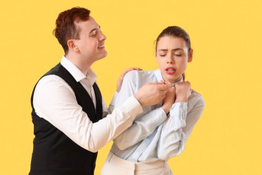 İş adamı, kadın meslektaşını sarı arka planda taciz ediyor. Taciz konsepti