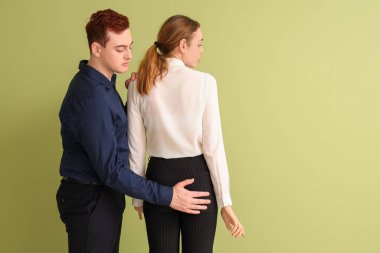 Business man touching his female colleague's butt on green background. Harassment concept