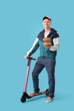Yiyecek konteynırları ve mavi arka planda scooterı olan erkek kurye.
