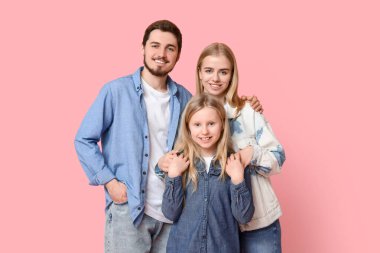 Pembe arka planda şık kot elbiseli mutlu bir aile.