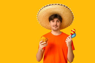 Sarı arka planda sombrero, marakas ve tortilla cipsi olan genç bir adamın portresi. Ulusal Tortilla Cipsi Günü kutlaması
