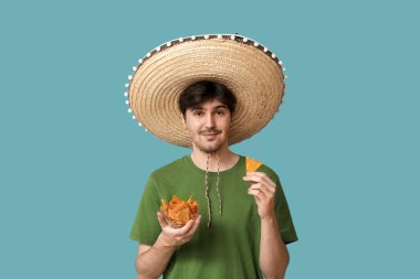 Mavi arka planda sombrero ve tortilla cipsi olan genç bir adamın portresi. Ulusal Tortilla Cipsi Günü kutlaması