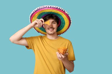 Mavi arka planda sombrero ve tortilla cipsi olan genç bir adamın portresi. Ulusal Tortilla Cipsi Günü kutlaması