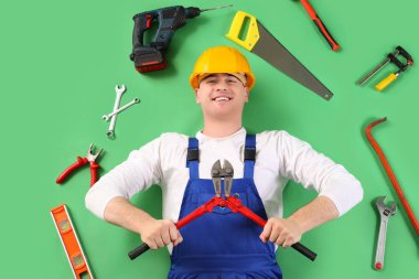 Yeşil arka planda iş araçları olan erkek inşaatçı, üst görünüm