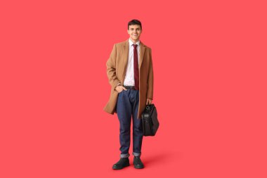 Ceketli genç bir adam ve kırmızı arka planda çantalı şık bir kravat.