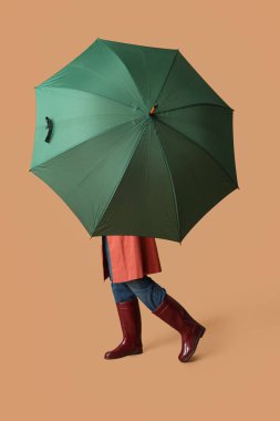 Bej arka planda şemsiyesi açık genç bir kadın.