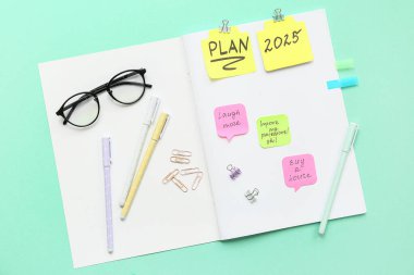 Yapılacaklar listesi boş olan defter, Cyan arka planında yapışkan notlar ve kırtasiye malzemesi. Yeni yıl hedefleri kavramı