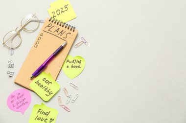 Planlar yapmak için yapışkan notlar, gri arka planda not defteri ve gözlük. Yeni yıl hedefleri kavramı