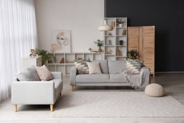 Oturma odasında rahat koltuklar ve raf ünitesi var.