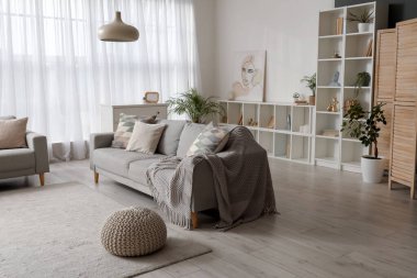 Oturma odasının içinde yastıklar ve ekoseli rahat bir kanepe.