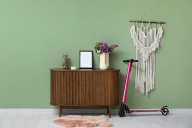 Şık oturma odasındaki çekmecelerin yanında siyah elektrikli scooter.