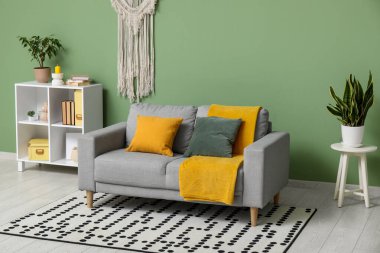 Rahat kanepesi, yastığı, çiçekleri ve sarı ekoseli oturma odası.