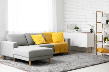 Rahat kanepesi, raf ünitesi ve sarı ekoseli oturma odası.