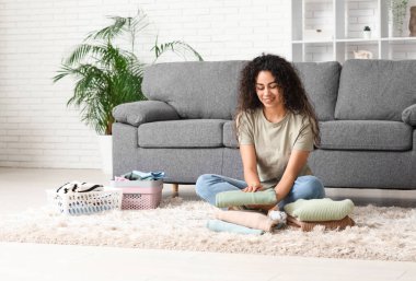 Güzel, genç, mutlu, Afro-Amerikan kadın. Temiz giysileri evde katlıyor.