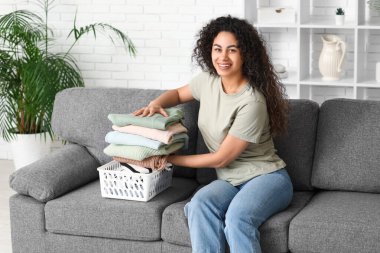 Güzel, genç, mutlu, Afro-Amerikan kadın. Temiz giysileri evde katlıyor.