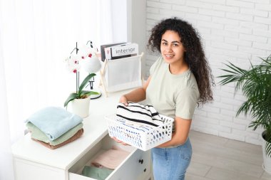 Güzel bir Afro-Amerikalı kadın evde temiz giysiler giyiyor.