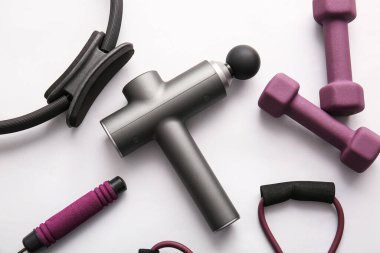 Gri arkaplanda vurmalı masaj aleti ve spor malzemesi kompozisyonu