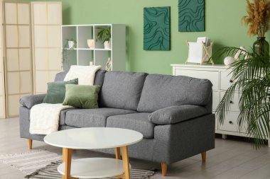 Yumuşak kanepesi, sehpası ve raf ünitesi olan şık bir oturma odası.