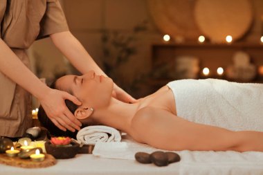 Koyu renk kaplıcada masaj yaptıran genç bir kadın.