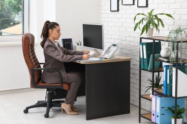 Şık ofisteki işyerindeki koltukta evrak işi yapan kadın ofis çalışanı.