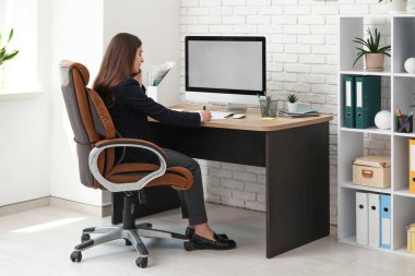 Cep telefonu kullanan ve işyerindeki koltukta oturan kadın ofis çalışanı.