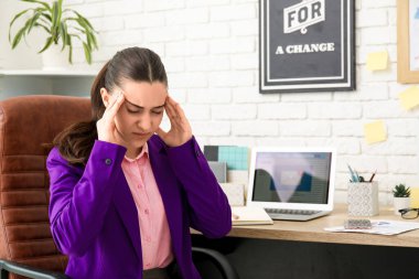İş yerinde başağrısı çeken genç bir kadın.