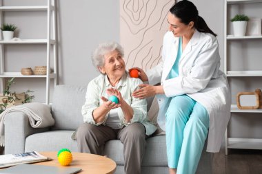 Evde masaj topları olan yaşlı bir kadın ve fizyoterapist.