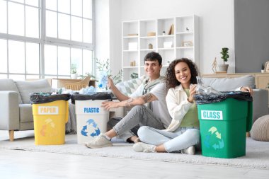 Evlerinde çöp kutularını düzenleyen genç bir çift. Geri dönüşüm kavramı