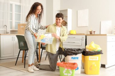 Mutfaktaki çöpleri düzenleyen çöp konteynırları olan genç bir çift. Geri dönüşüm kavramı