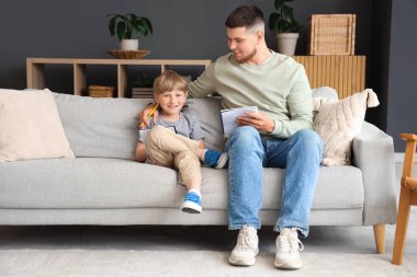 Genç baba evdeki oğluna ev ödevlerini anlatıyor.