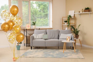 Evdeki bej duvarın yanında kanepesi ve sehpası olan güzel altın hava balonları.