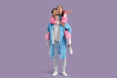 Leylak arkaplanda yağmurluk giyen genç bir çift