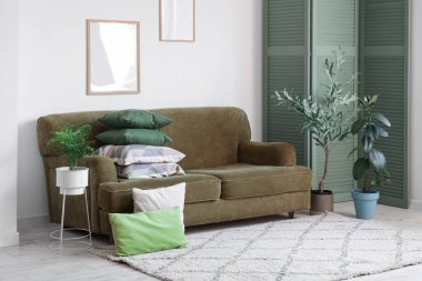 Yeşil kanepenin üzerinde yastık yığını olan oturma odasının içinde.