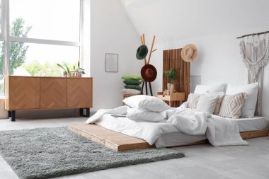 Yatak odasının içinde yumuşak yastıklı ve buruşuk battaniyeli rahat bir yatak.