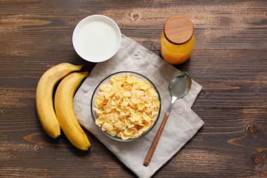 Peçete, muz ve tahtadan arka planda mısır gevreği olan kase.