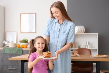Sevimli küçük kız ve annesi mutfakta lezzetli tost yapıyorlar.