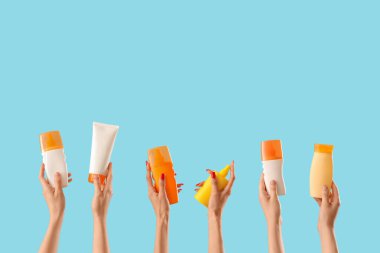 Mavi arka planda güneş kremi sürmüş kadın elleri