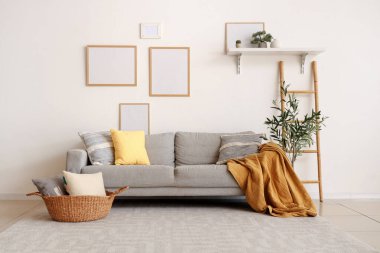 Güzel oturma odasının içinde rahat bir kanepe, ekose, yastıklar ve zeytin ağacı var.