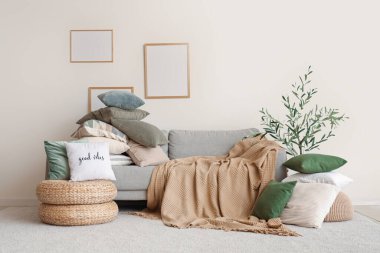 Şık oturma odasında bir yığın yumuşak yastık ve gri kanepe.