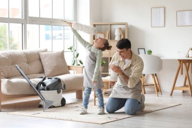 Genç baba ve kızı evde toz alıcılarla eğleniyorlar.