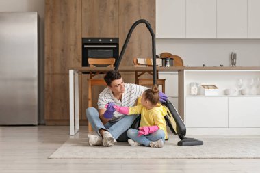 Genç babası ve kızı mutfakta elektrikli süpürgeyle.