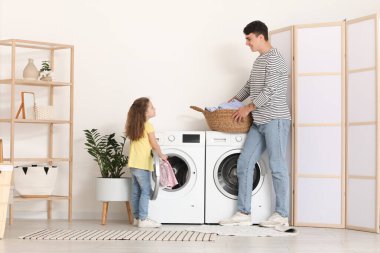 Genç baba ve kızı banyoda çamaşır sepetiyle