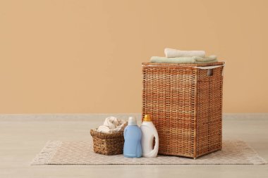 Çamaşır sepetinin üstünde bej duvarın yanında jöle var.