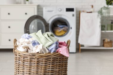 Çamaşır odasında çamaşır makinelerinin yanında kirli çamaşırlarla dolu bir sepet.