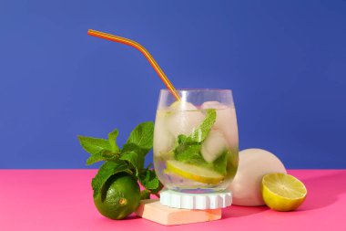 Bir bardak taze mojito. Mavi arka planda pembe masada saman var.