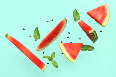 Uçan taze karpuz parçaları tohumlar ve turkuaz arka planda nane şekeri.